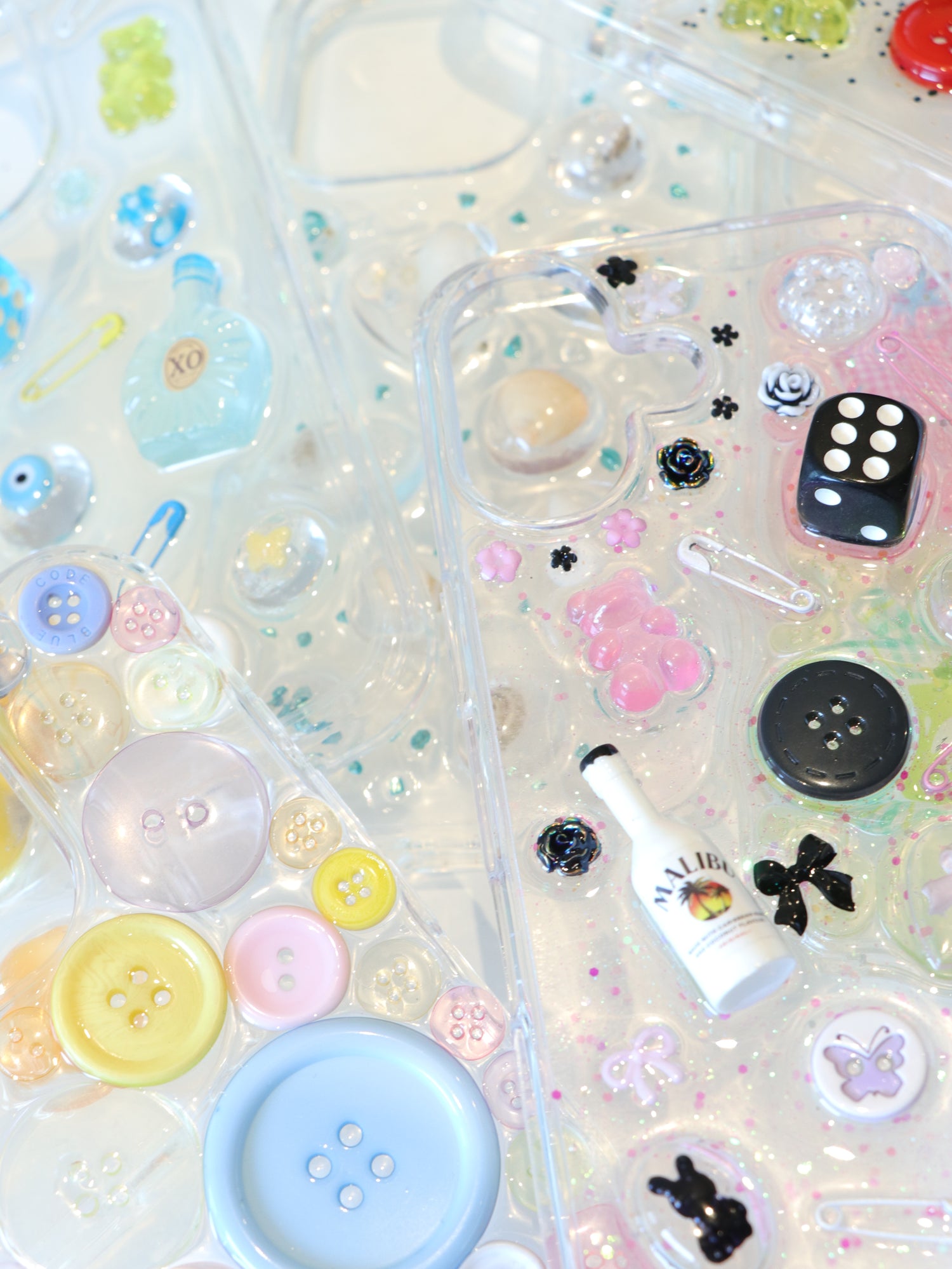Transparent phone case with colorful buttons, flowers, and other decorative elements on a white background
