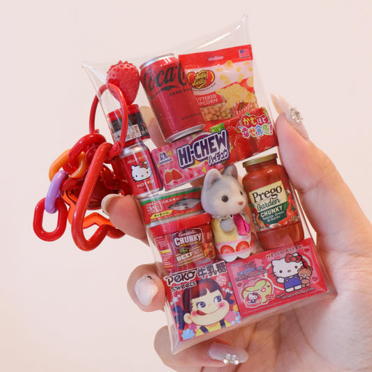 Hand holding a small packaging of miniature food items and toys with a plain background