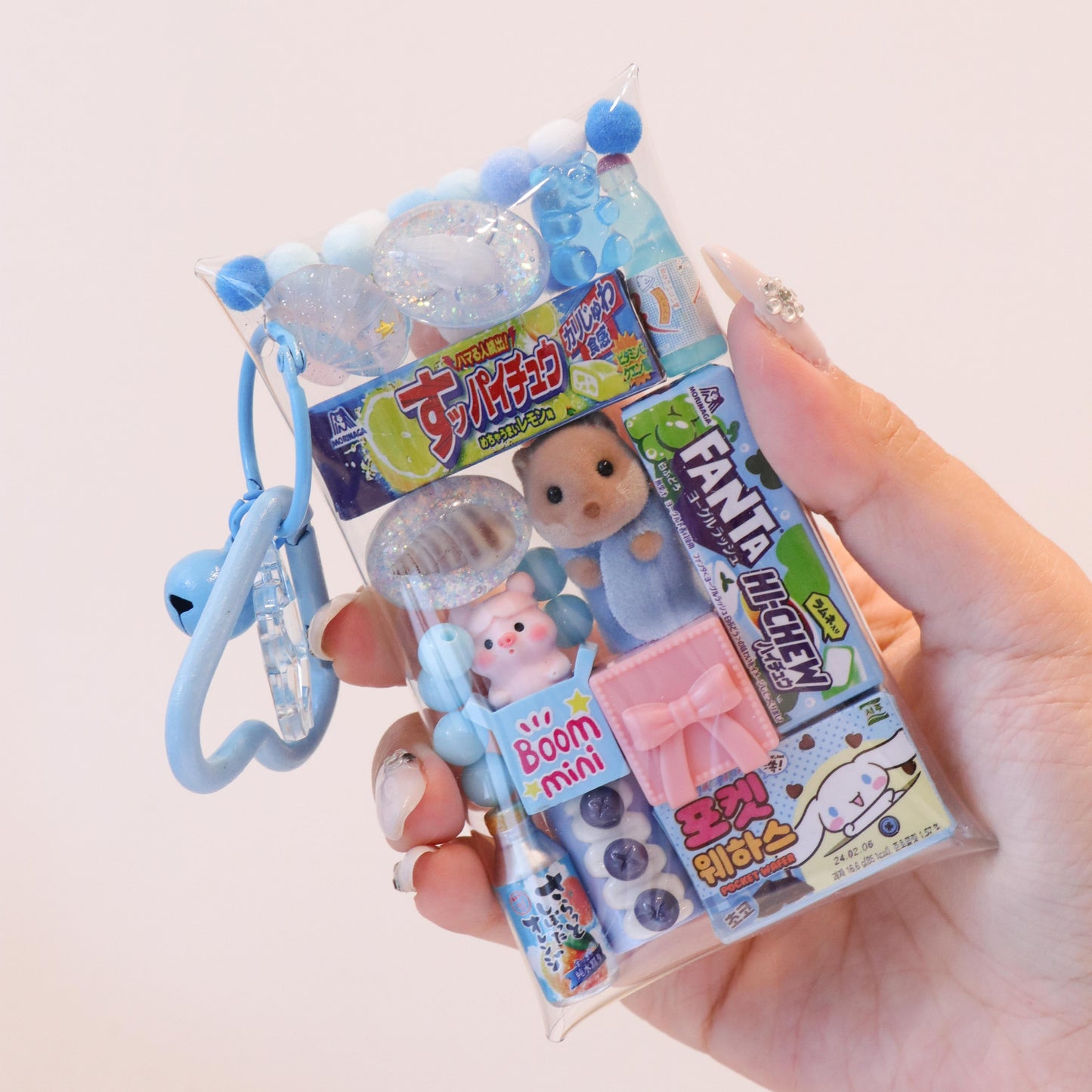 Hand holding a small toy package with a keychain on a light background